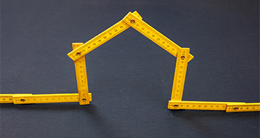 A creative tape measure shaped like a house, symbolizing the accurate measurement of a home's square footage.