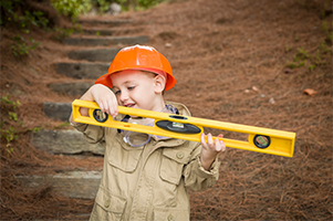 Small boy wearing a hardhat and holding a level