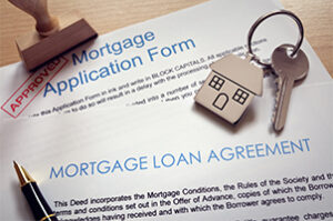 Co-Borrower mortgage loan documents and a house-shaped keyring on a table.