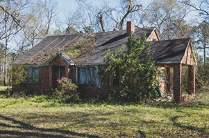 Picture of an overgrown and rundown house in disrepair, perfect for a fixer-upper home project.